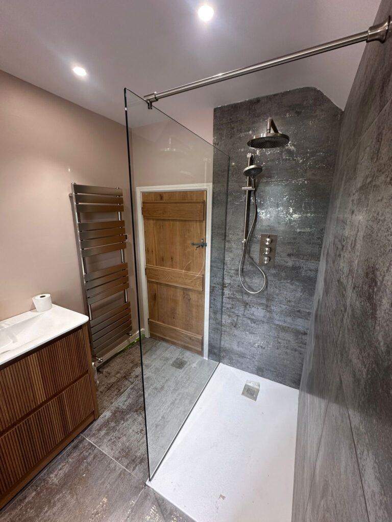 Frameless toughened glass shower screen installed beside tiled wall in modern bathroom