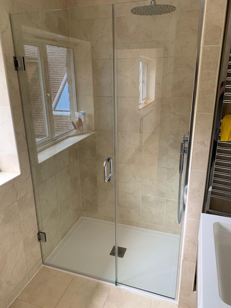 Grey mirror splashback installed behind kitchen worktop and hob with white shaker cabinets
