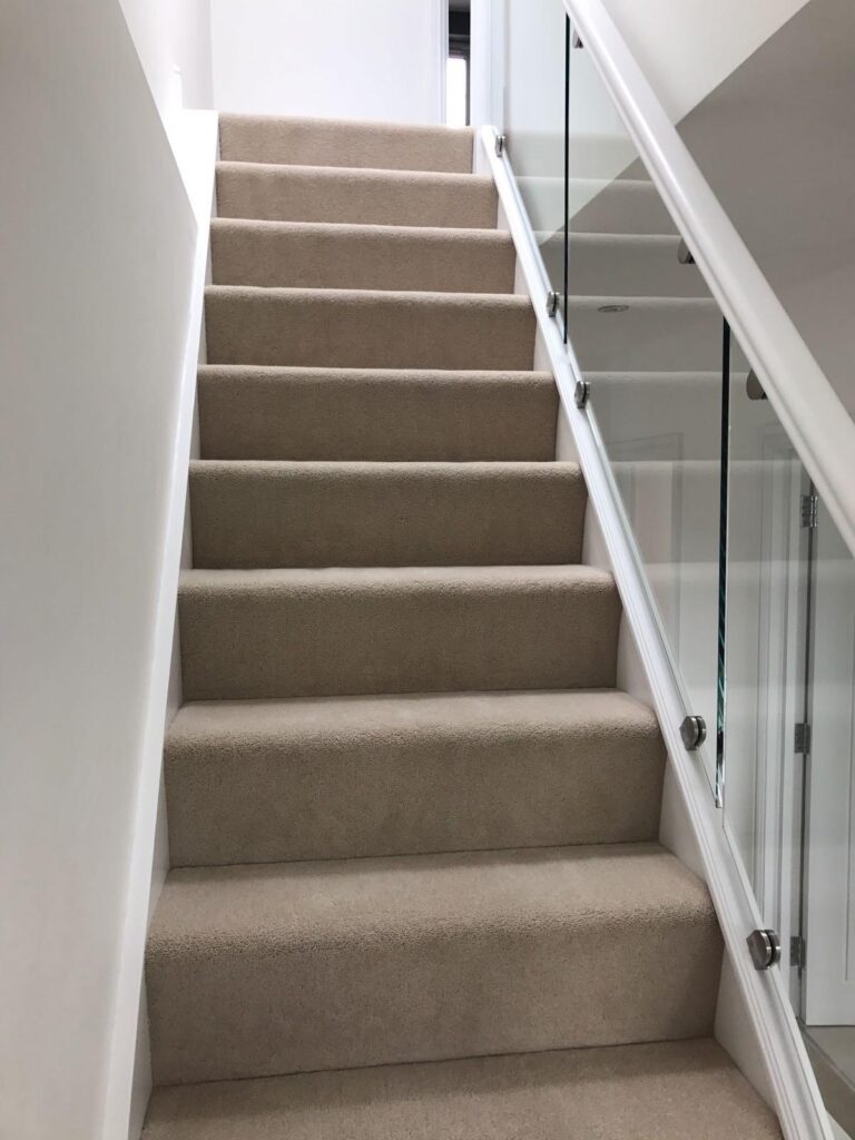 Modern frameless glass balustrade installation with chrome handrail on staircase